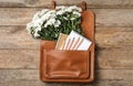 Leather briefcase with stationery and flowers on wooden table, top view. Teacher`s Day