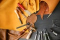 Leather with craft tools on dark wooden background