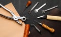 Leather crafting DIY tools lies on natural black and brown leather. Royalty Free Stock Photo