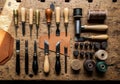 Leather crafting tools arranged on a wooden workbench include knives, awls, stitching chisels, and Royalty Free Stock Photo