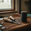 A leather crafting workspace is depicted, featuring a roll of black thread and two awls Royalty Free Stock Photo