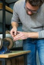 Leather craftsman sharpens knife for cutting leather on sander. Handmade concept. Concept of small business to create leather