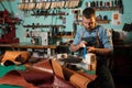 Leather craftsman working with natural leather using hammer. Handbag master at work in local workshop. Handmade concept.