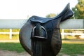 Leather horse saddle on wooden fence.