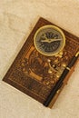 Leather journal notebook with a fountain pen and antique compass in sand. Royalty Free Stock Photo