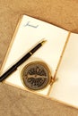 Leather journal, with the word journal on a page, with a fountain pen and antique compass in sand. Royalty Free Stock Photo