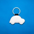 Leather key ring in car shape on blue paper background. Blank key chain for your design Royalty Free Stock Photo
