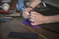 Leather maker cut leather with utility knife on wooden working table