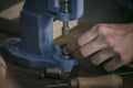 Leather maker working with professional hand press on wooden table