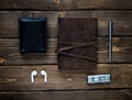 leather notebook with a metal ballpoint pen  wallet  headphone and a pocket multitool on wooden background Royalty Free Stock Photo