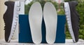 Leather orthopedic insoles in front of blue box and pair of sport shoes. Outdoors