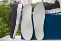 Leather orthopedic insoles in front of blue box and pair of sport shoes. Outdoors