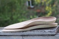 Leather orthopedic insoles on an old wooden board outdoors.