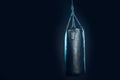 Leather punching bag hanging on steel chains on black.