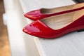 Leather red women& x27;s shoes on a white wooden shelf. Fashion, minimal fashion concept, women& x27;s shoes, accessories. red