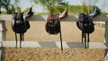 Leather Saddles Hanging On The Wooden Fence In The Sandy Arena - Horse Riding Royalty Free Stock Photo