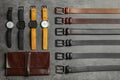 Leather wallet, belts and wristwatches on stone table, flat lay