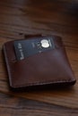 Leather wallet with a black bank credit card on a wooden base