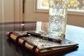 a leatherbound journal, fancy pen, and a tall glass of water on the table