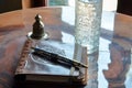 a leatherbound journal, fancy pen, and a tall glass of water on the table