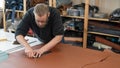 Leatherworker measuring and cutting leather in workshop. Royalty Free Stock Photo