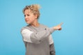 Leave me! Resentful woman with curly hair in sweatshirt pointing sideways, showing get out gesture