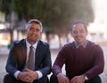 Leave the talking to us. Portrait of two businessmen having a discussion while seated outside on steps.