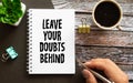 Leave your doubts behind - handwriting on a napkin with a cup of espresso coffee