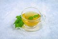 Leaves of fresh green nettle and a clear glass cup of herbal nettle tea on a gray concrete table. Royalty Free Stock Photo