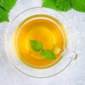 Leaves of fresh green nettle and a clear glass cup of herbal nettle tea on a gray concrete table. Top view. Royalty Free Stock Photo