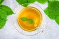 Leaves of fresh green nettle and a clear glass cup of herbal nettle tea on a gray concrete table. Top view. Royalty Free Stock Photo