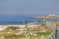 View of woman taking pictures on pedestrian wooden walkway, beach and sea as