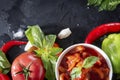 Lecho  with a sprig of green Basil, tomato slices, red chili pepper, garlic, ice cubes, on a black background, sauce Royalty Free Stock Photo