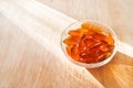 Lecithin gel pills in a round glass bowl with sun light on wooden background. Soy and sunflower lecithin benefits for