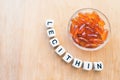 Lecithin gel pills in a round glass bowl and with the word Lecetin from the letters of cubes on a light wooden background. Soy