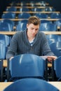 Lecture hall, college and man with thinking, student and knowledge with exam and education. Person, writing and guy in