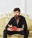 Lecturer sit on sofa and reading book, white wall background. Elite leisure concept. Scientist, professor on thoughtful