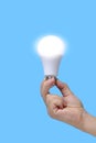 LED eco friendly light bulb in hand on blue background. Royalty Free Stock Photo