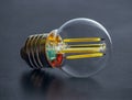LED filament light bulb with an amber-colored glass shell on the background of dark background. Close-up
