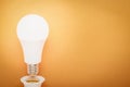 LED lamp twisted out of a socket on an orange background with copy space: energy-saving concept and Earth Hour Royalty Free Stock Photo