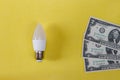 LED lamp on yellow background and dollas