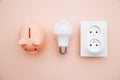 LED light bulb, power socket and pink piggy bank. Power energy economy