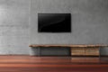 Led tvs on concrete wall with wooden furniture in empty living r