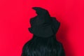 Ledy in a witch costume facing a red background