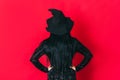 Ledy in witch costume keeps her hands on her hips facing red background Royalty Free Stock Photo