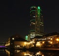 Leeds canal wharf at night with brightly illuminated buildings and lock reflected in the water and glowing against a dark sky