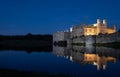 Leeds Castle in Kent UK, illuminated at night and reflected in the surrounding water. Royalty Free Stock Photo