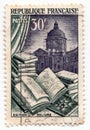 An old french postage stamp showing an open book with illustration and a library in the background Royalty Free Stock Photo