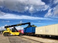 A heavy lifting machine loading shipping containers onto a train