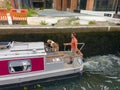 A man and his dog crossing a canal of RIver Aire in Leeds on a canal boat. Such boats are hired for family holidays along historic